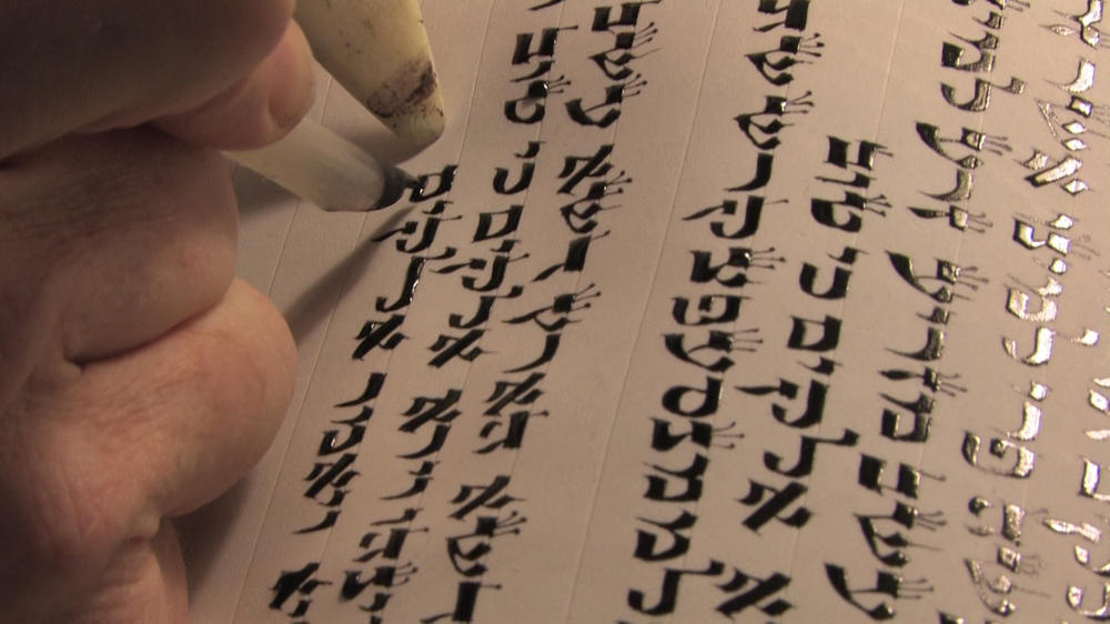 Auftragen der Tinte und Formung der Buchstaben beim Schreiben einer Torarolle