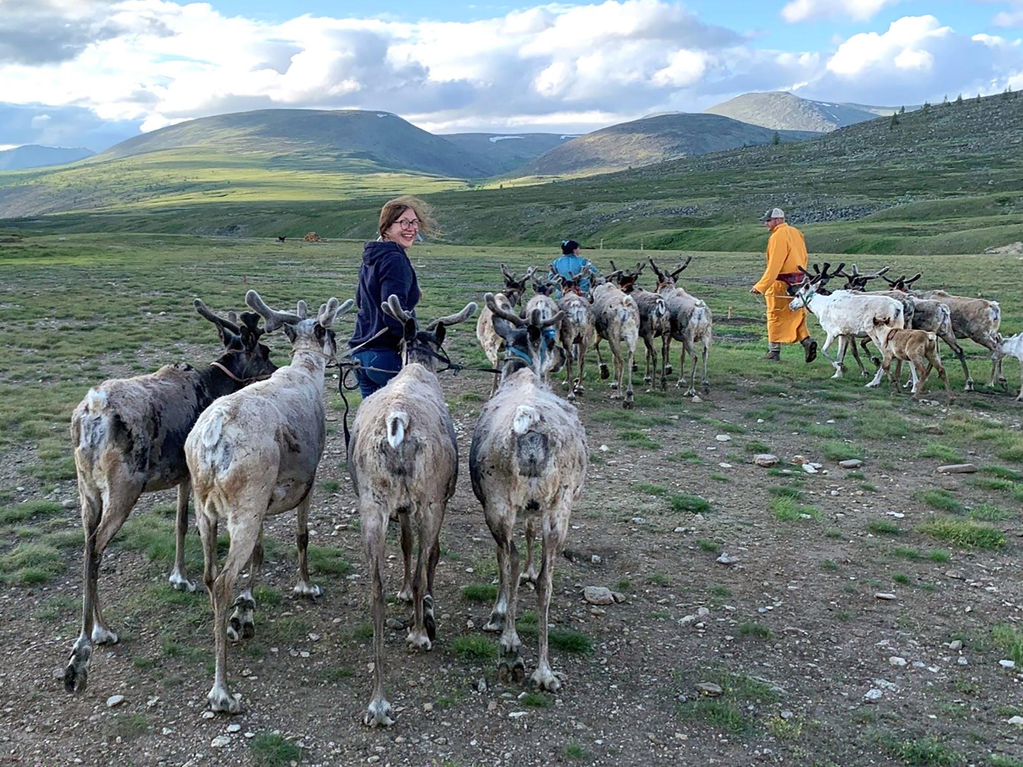 Kooperationspartner William Taylor, Universität Boulder Colorado, (rechts) und Henny Piezonka (links) helfen Dukha-Hirten beim Anpflocken der Rentiere während eines Gewitters, Sommer 2023.